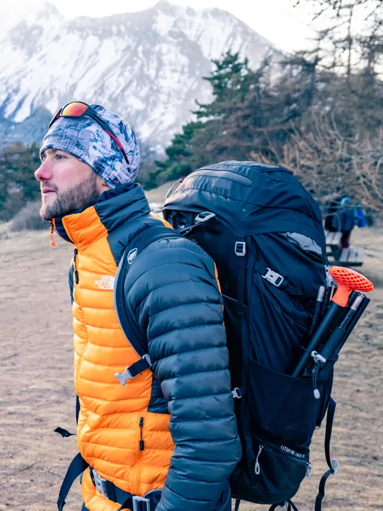 Luciano Fochi con zaino e piumino arancione, in montagna